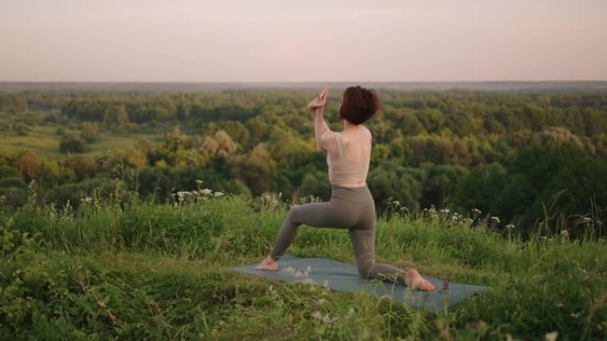 在慢动作中，一名年轻女子通过在顶部进行平衡和伸展来进行瑜伽练习。身体和灵魂的平静与和平平衡。身体弯曲