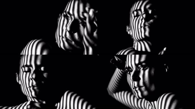 女性的脸和身体在条纹的阴影中。黑白相间的艺术镜头。