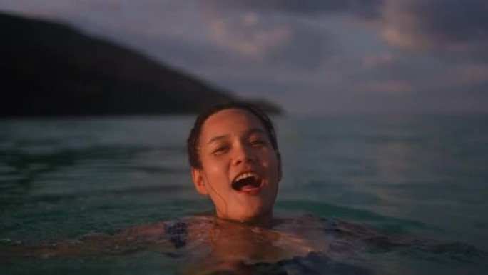 微笑的年轻女子在海里游泳