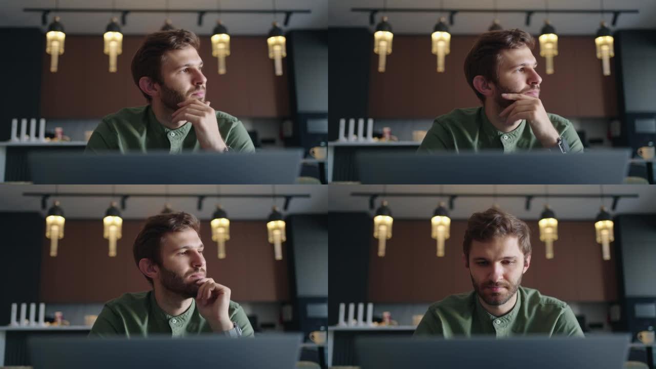 男人在家里或在共同工作的空间里用笔记本电脑工作，英俊的大胡子男人的正面肖像