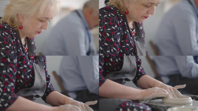 一位年长的女大师在慢动作的陶工轮上工作。用陶瓷和粘土亲手做盘子