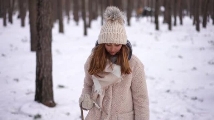 无忧无虑美丽的高加索少女走在冬季公园拉雪橇扔雪。前视图多莉拍摄了放松自信的青少年享受周末户外休闲的肖