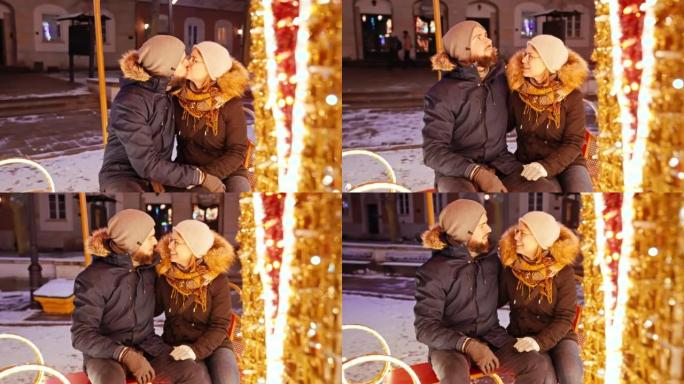 在下雪的圣诞节之夜，一对夫妇在慢动作中一起亲吻旋转木马