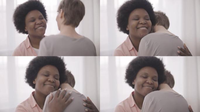 黑人妇女微笑着拥抱高加索女性朋友，信任的关系