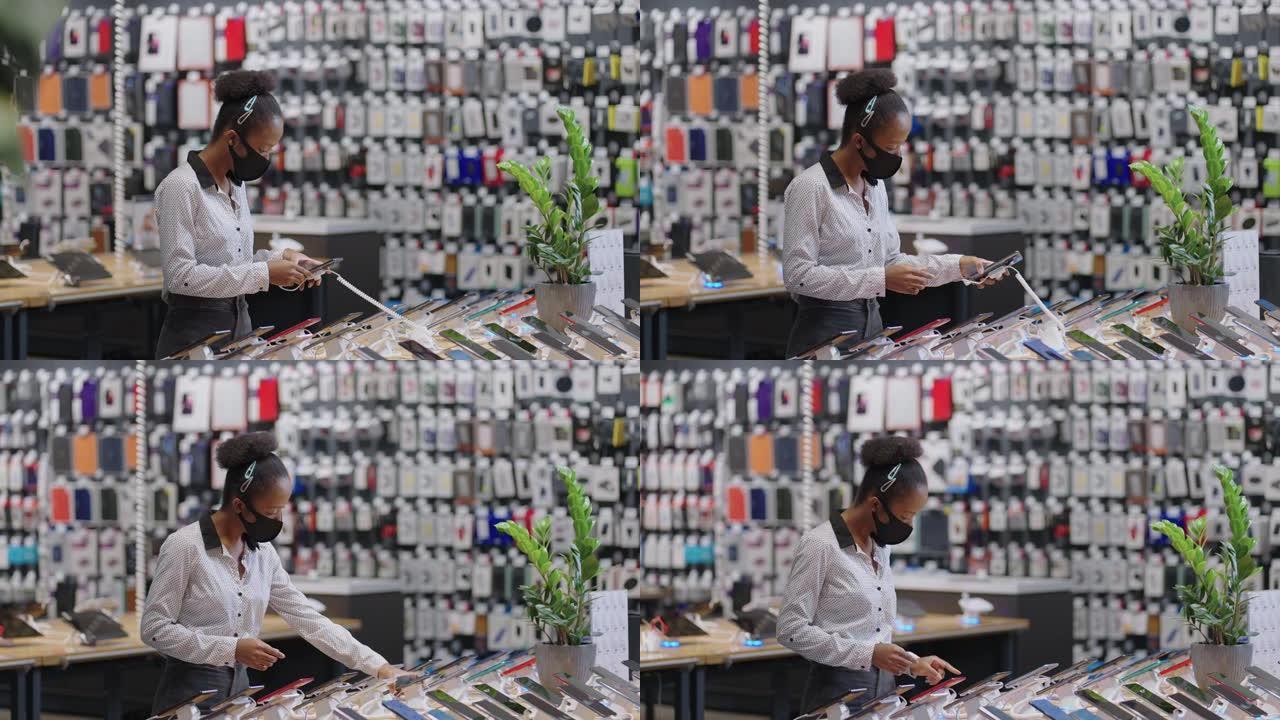 美国黑人女性购物者在新型冠状病毒肺炎大流行期间选择电子商店的手机，戴着口罩的黑人女性