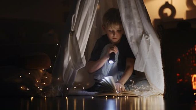 孩子晚上看书，坐在帐篷里，灯笼照明，快乐的童年