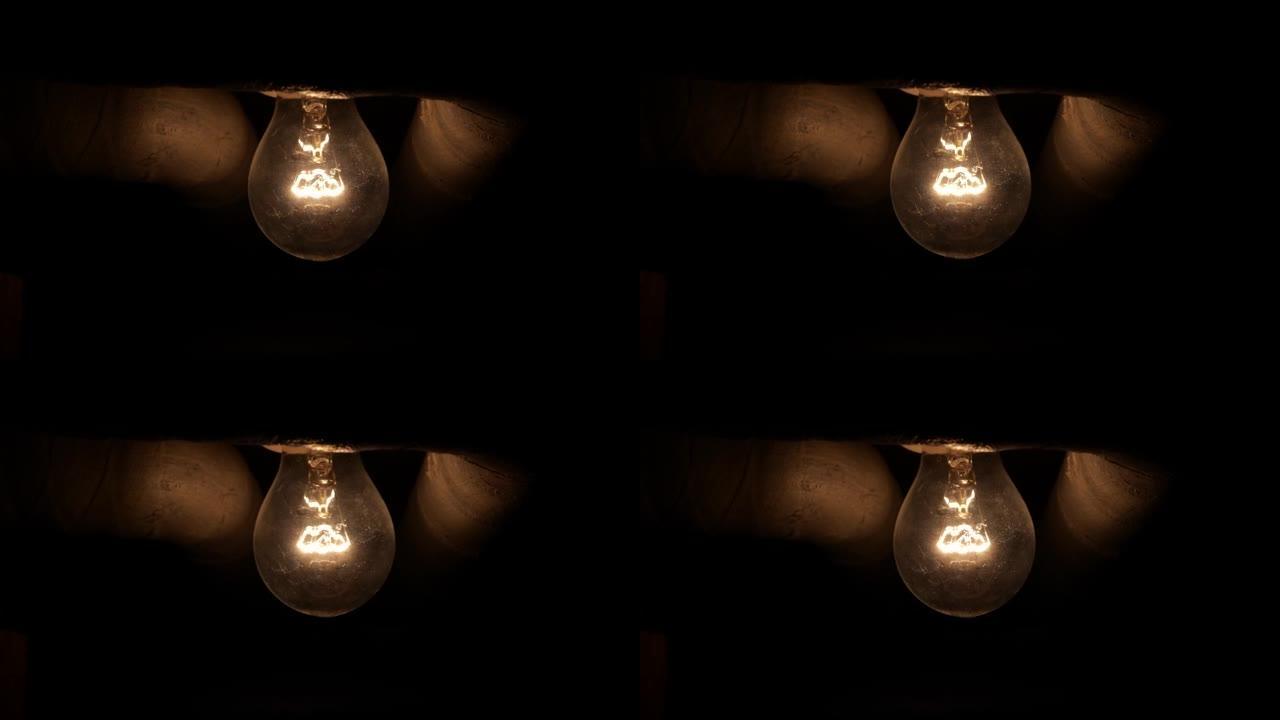 天花板固定装置中的旧白炽灯泡，在地下地窖中燃烧。特写镜头，低调，黑暗场景，实时，没有人