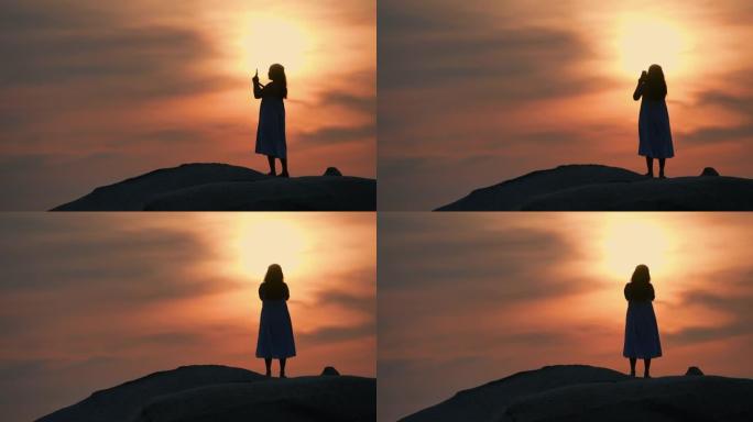 女人在日落时用手机拍照