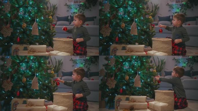 5-6岁的男孩，在圣诞节前夕在圣诞树上装饰玻璃球