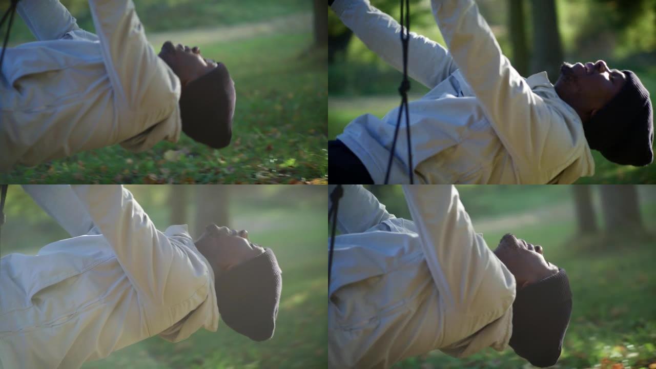 非洲民族十几岁的男孩在秋千公园的秋千上来回摆动