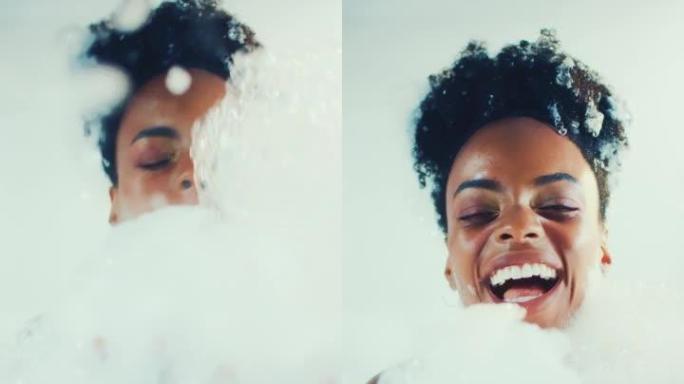 快乐美丽的非洲女人快乐而轻松地覆盖着沐浴泡沫。慢动作，垂直拍摄。