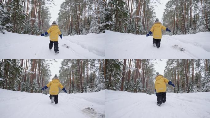 一个3-4岁的小男孩在冬季森林中奔跑，穿着黄色外套从后面慢动作观看。冬季乐趣和积极娱乐的概念，自由和