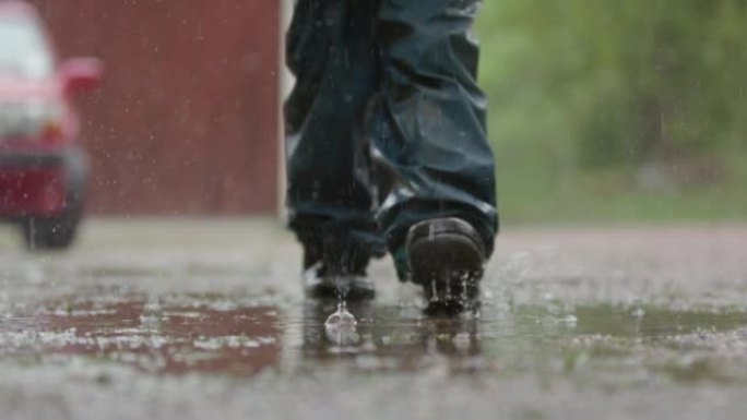 慢动作，孩子的腿在大雨中穿过水坑