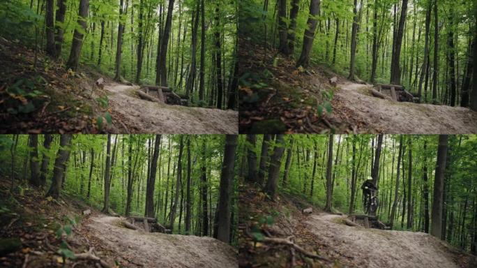 一个专业的山地自行车骑行者在相机上高速骑行并跳过森林障碍物和蹦床的史诗般的镜头。穿越森林的大气镜头