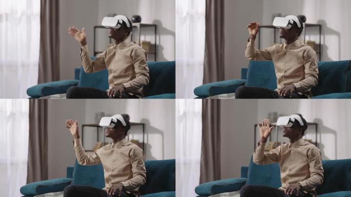 虚拟现实娱乐小工具，头戴式显示屏的黑人独自坐在房间里，用手滑动虚拟屏幕