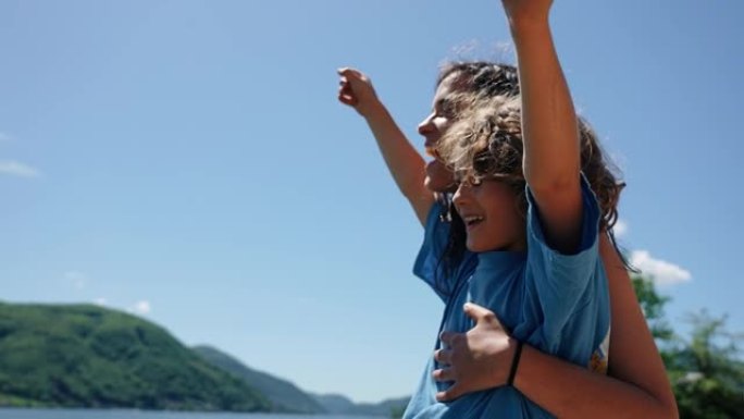 母亲和小男孩一起看着湖泊和山脉的景色，为生活感到兴奋