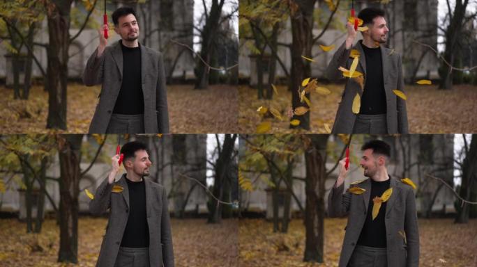 快乐的人举着雨伞，树叶慢动作落下。高加索人快乐的人在户外秋季公园四处寻找乐趣的肖像。