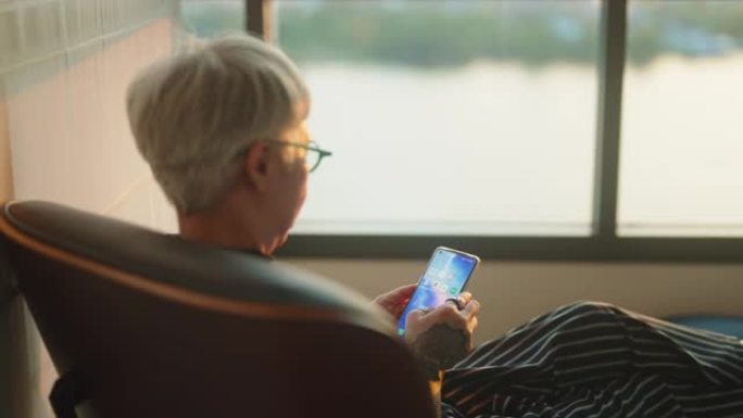一位老年妇女用智能手机透过窗户拍照。