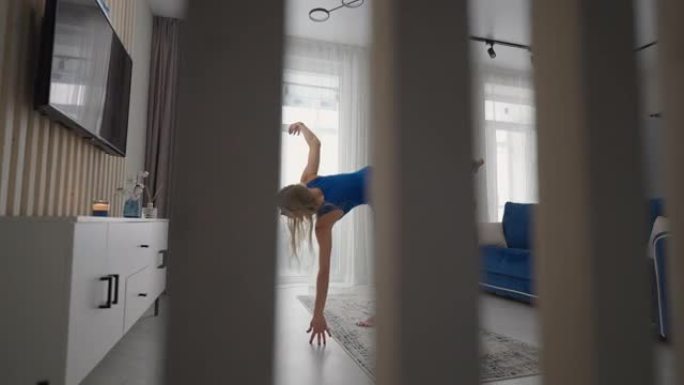 年轻女子坐在地毯上冥想，做伸展运动，做瑜伽，早上在家的蓝色运动服灯光室。女人在家练习瑜伽