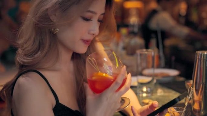 年轻的亚洲人在手机上玩耍，感到悲伤，晚上在酒吧和餐馆喝鸡尾酒。
