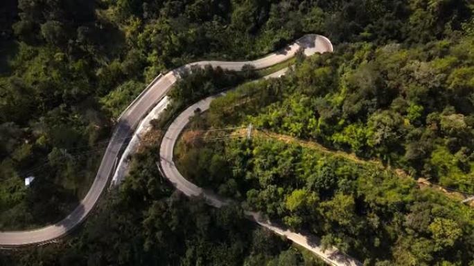 泰国北部森林中的绿色道路和山上汽车行驶的鸟瞰图。