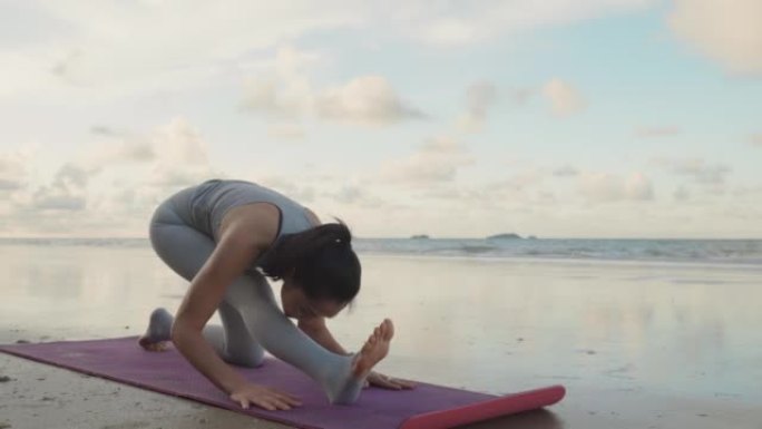 4k视频片段，一个美丽的瑜伽女人在晨曦中的海滩上，享受生活锻炼，度假，健康，旅行，生活方式