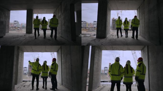 土木工程师正走在在建建筑中，女性和男性专业建筑商的后视