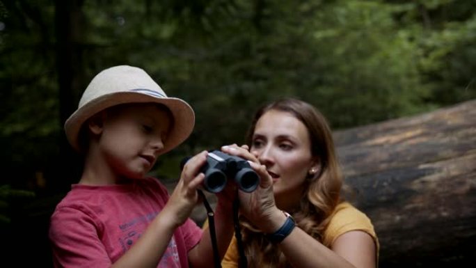 小男孩和妈妈鸟在树林里看着双筒望远镜