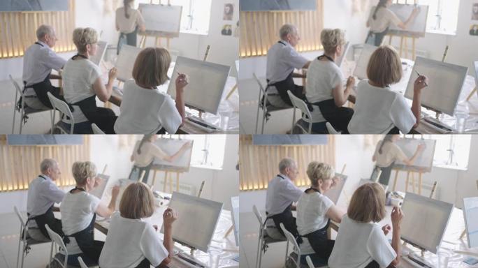 慢动作老人参加绘画课程。老师帮助参加绘画课程的养老金领取者绘画。一群退休的朋友在绘画课上