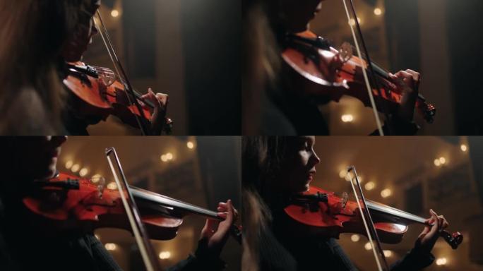 穿着黑色衣服的女小提琴手在黑暗的爱乐音乐厅演奏经典音乐