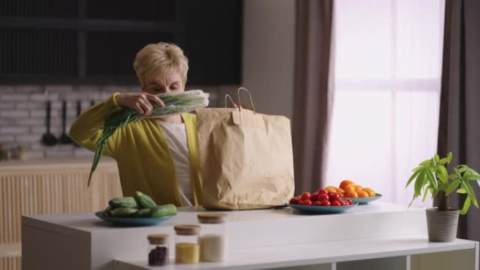 老年妇女从超市返回，并打开装有食物的袋子，将物品放在厨房的桌子上