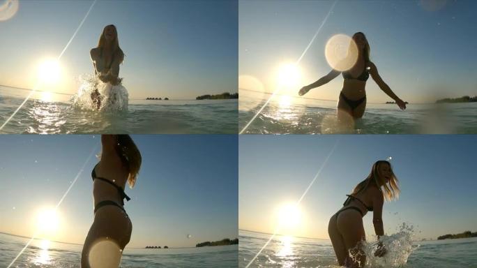 美丽的女人在热带水中享受日落。泼水