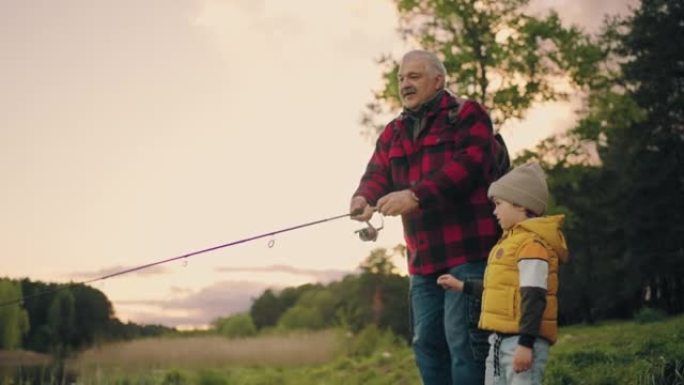 爷爷在教孙子在湖岸钓鱼，老人在扔鱼竿