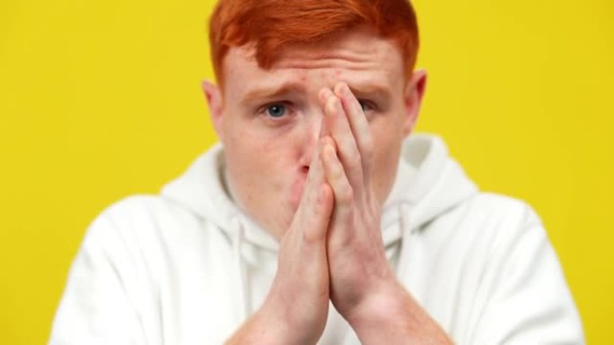 模糊的红头发受惊的男人在黄色背景下摩擦双手。害怕的高加索人恐慌症发作。压力和焦虑概念。