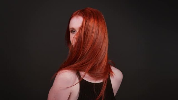 迷人的红发女人在镜头前扔她健康的长发。工作室镜头，超级慢动作