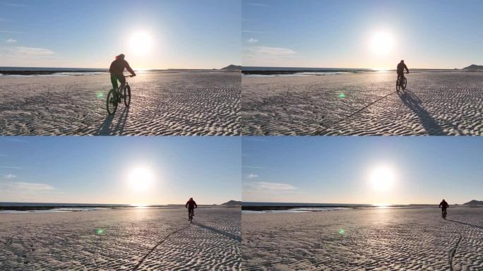 男子在空旷的海滩上骑自行车的鸟瞰图
