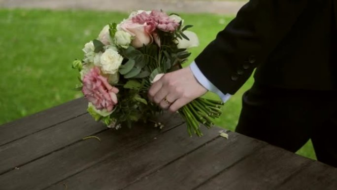 新郎在仪式前拿着婚礼花束。新娘的花束