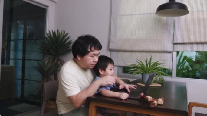 亚洲年轻父亲带着孩子在家工作