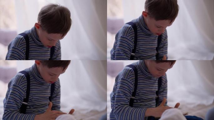 集中古玩自闭症男孩坐在舒适的室内智能手机上玩耍的肖像。专注的高加索儿童在手机游戏中享受游戏的基座镜头