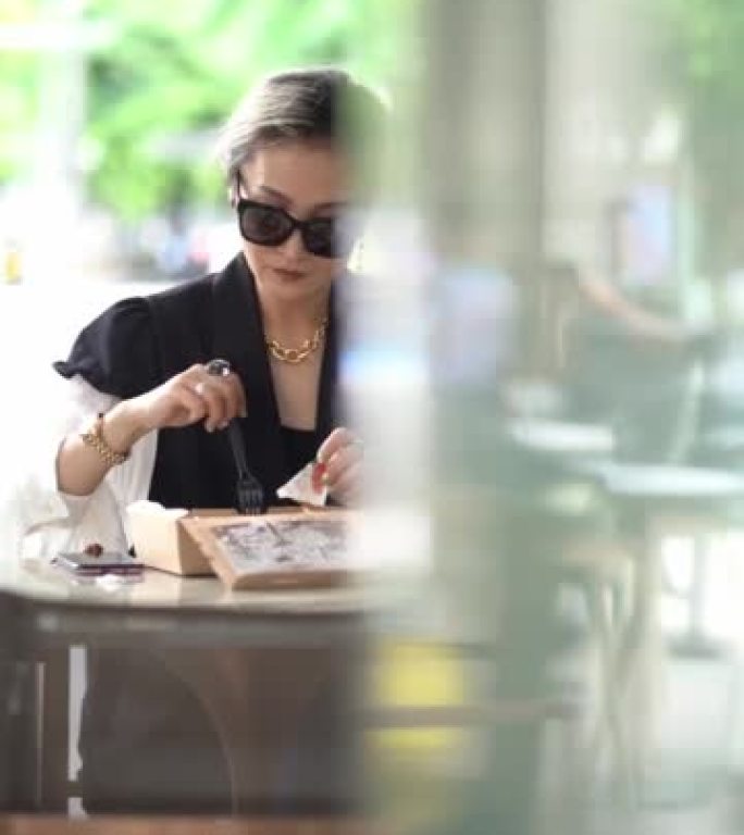 亚洲美女坐在咖啡店外面吃清淡的食物