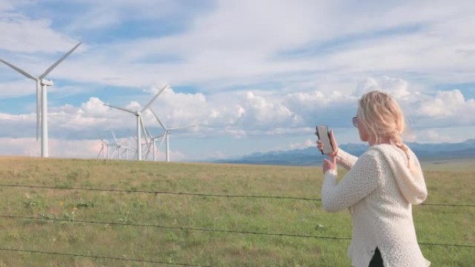 查看过去的女人到风力涡轮机和草原景观，远山