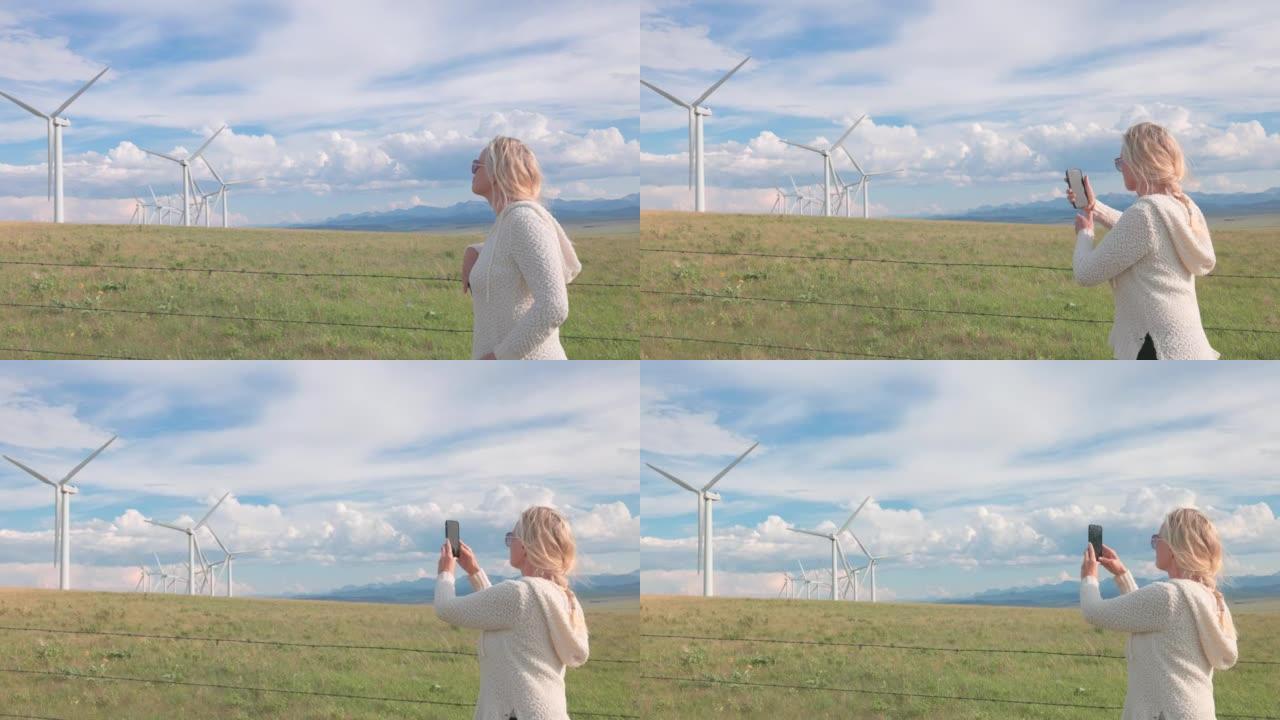 查看过去的女人到风力涡轮机和草原景观，远山