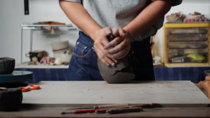 匿名男子在陶器工作室手工雕刻粘土。人准备产品用模具粘土。教育、商业、艺术天赋和创意手工制作的概念。