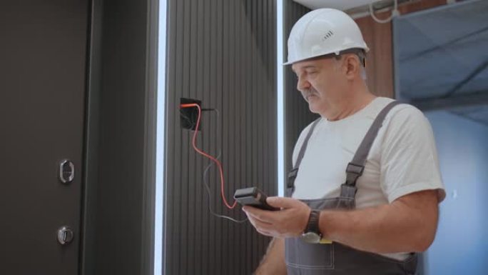 肖像电工在安装和维修后使用现代房屋系统检查灯具墙壁控制单元的操作