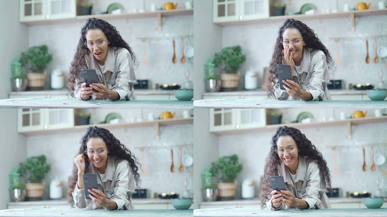 戴着眼镜的惊讶女人在家里看了手机留言后非常开心兴奋卷曲黑发看着智能手机屏幕