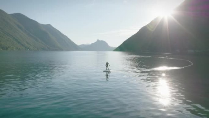 骑着电子箔的人在平静的湖上滑行和冲浪包围了我的山脉