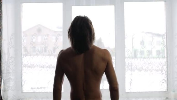 一个冬天的早晨，男人在窗边锻炼体操，晨练。