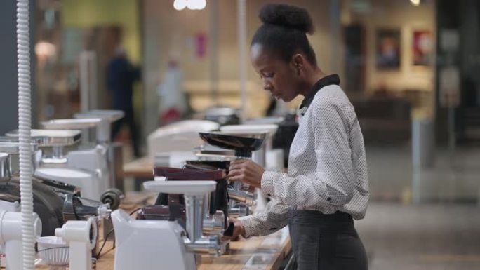美国黑人妇女在商店里看电动绞肉机，年轻的家庭主妇想购买厨房用的家用电器