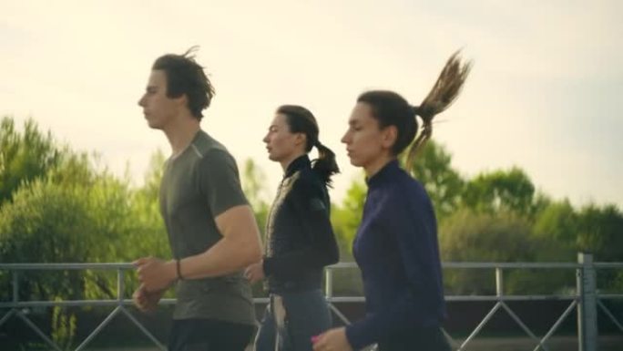 早晨的跑步者，两个年轻的女人和男人一起慢跑，健康的生活方式