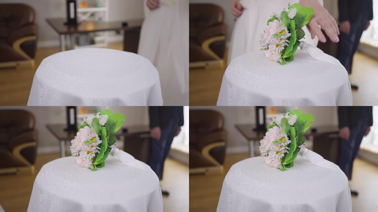 特写桌子，穿着婚纱的无法辨认的新娘慢动作通过，留下新娘花束。穿着西装的模糊新郎站在背景下。婚姻失败与